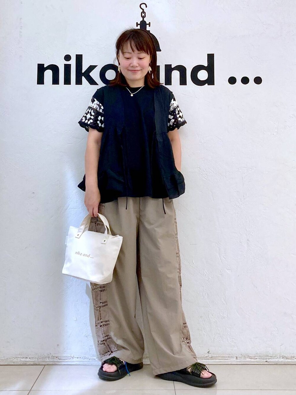 ホワイト系のトートバッグ、ブラウン系のその他パンツ、ブラック系のベストを着用したレディースの夏コーディネートの2枚目の写真