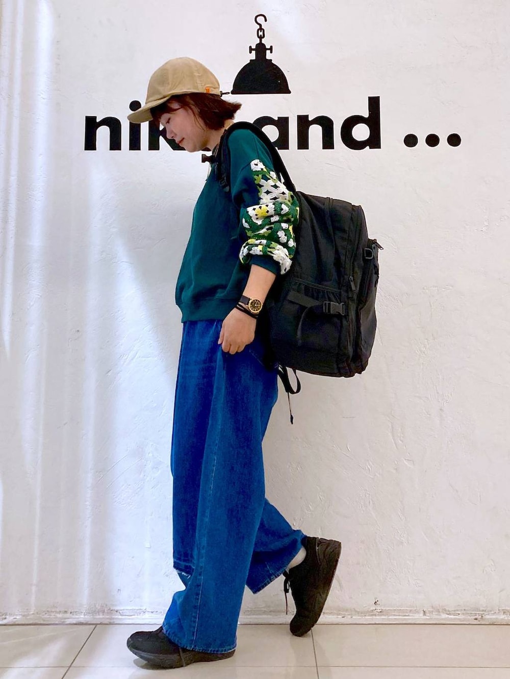 グリーン系のスウェット、ブルー系のデニムパンツ、ブラック系のバックパック/リュックを着用したレディースの秋コーディネートの3枚目の写真