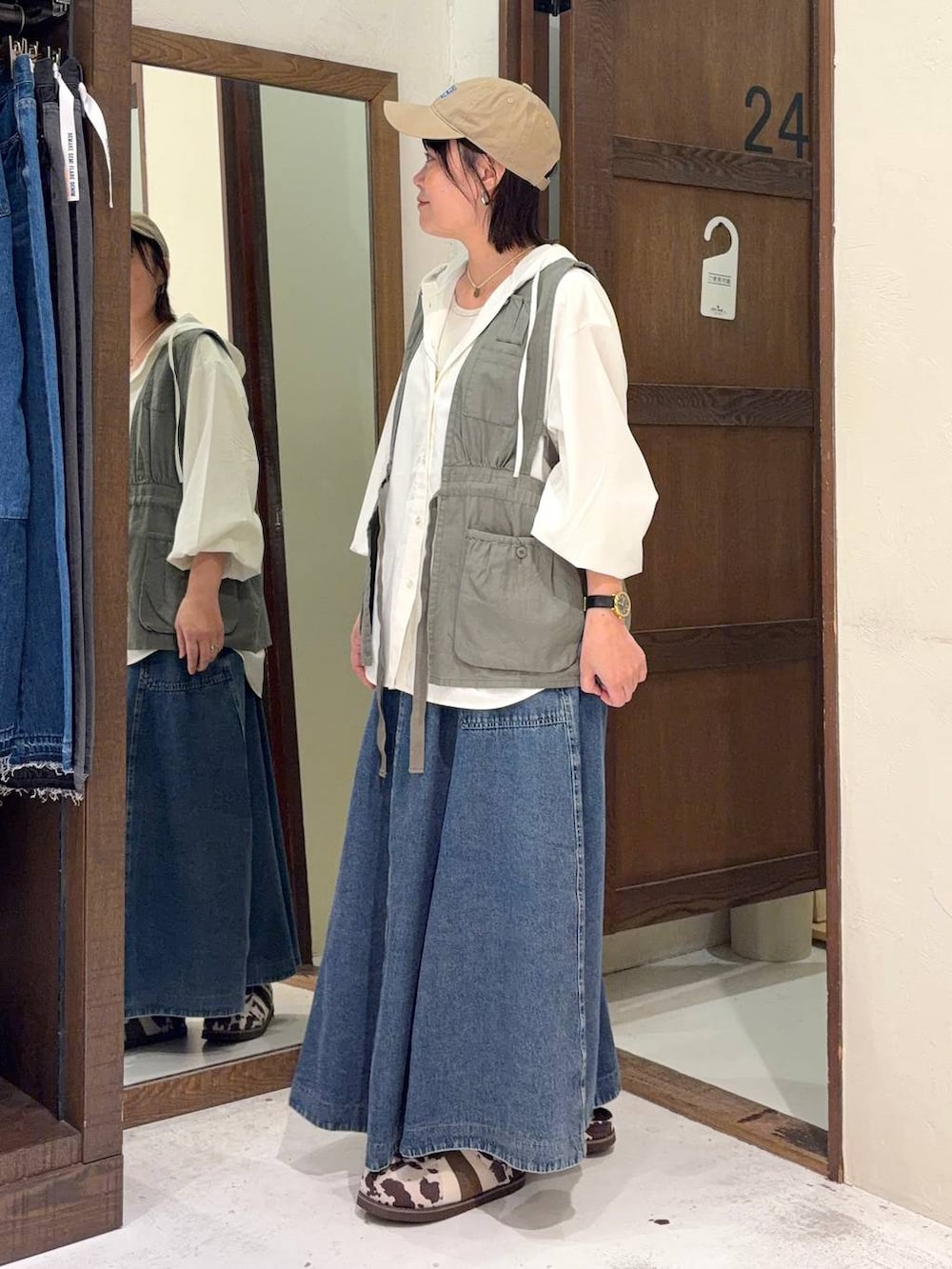 ブルー系のスカート、グリーン系のベスト、ホワイト系のシャツ/ブラウスを着用したレディースの春コーディネートの4枚目の写真