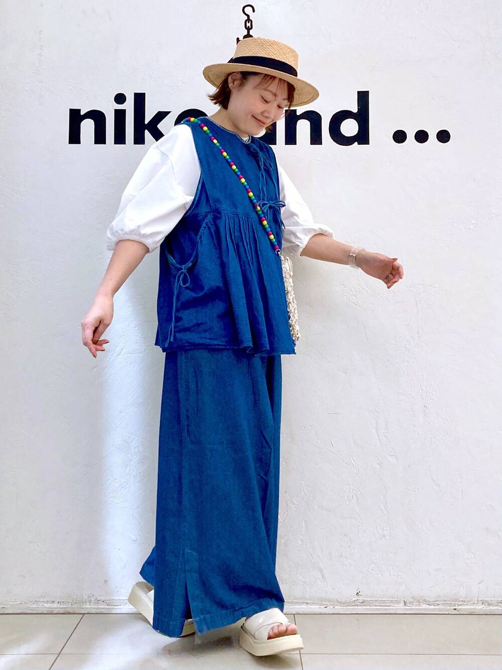 ベージュ系のショルダーバッグ、ベージュ系のサンダル、ホワイト系のTシャツ/カットソーを着用したレディースの夏コーディネートの3枚目の写真