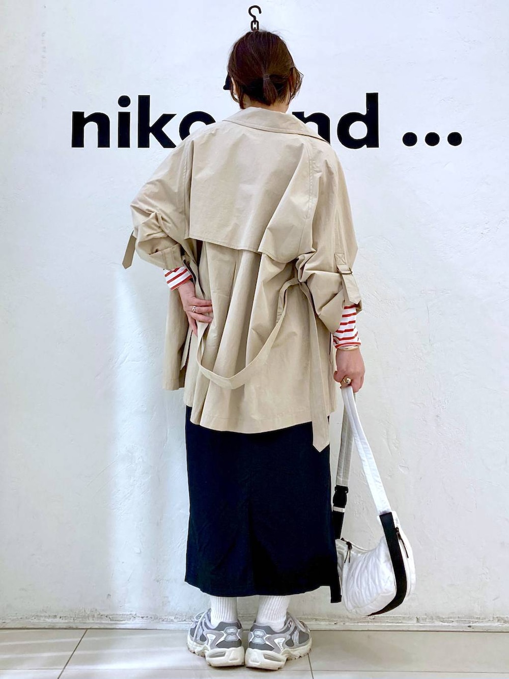 ベージュ系のトレンチコート、ベージュ系のショルダーバッグ、ブラック系のスカートを着用したレディースの春コーディネートの4枚目の写真