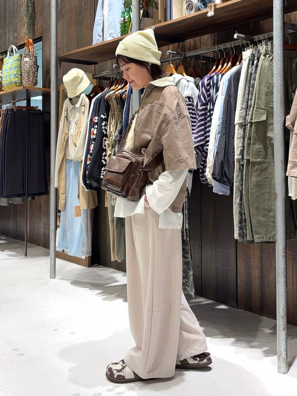 ブラウン系のショルダーバッグ、ベージュ系のベスト、ホワイト系のTシャツ/カットソーを着用したレディースの春コーディネートの4枚目の写真