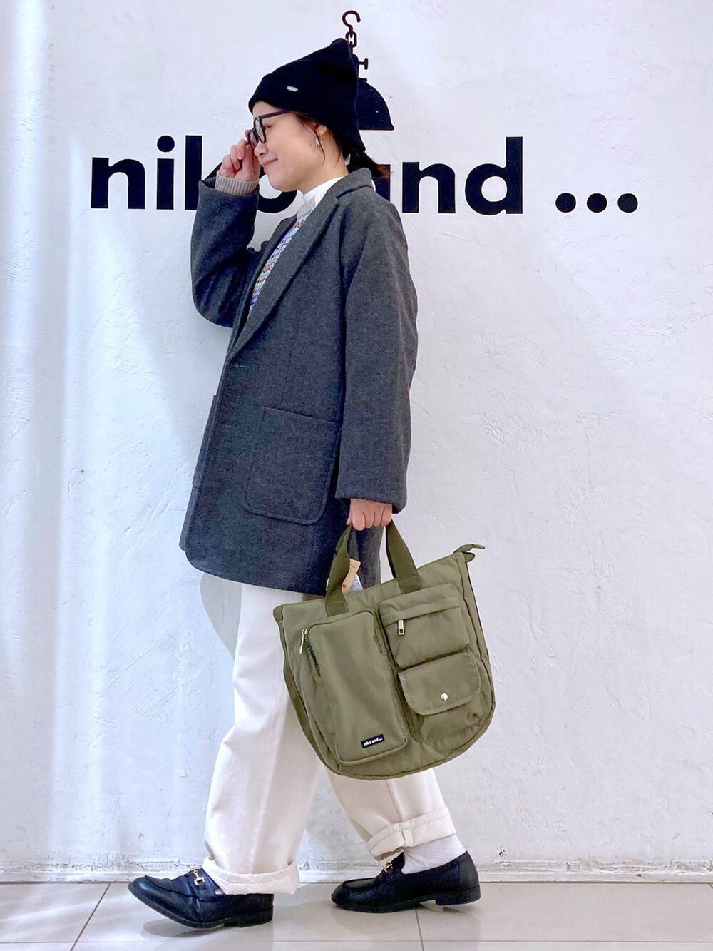 グレー系のテーラードジャケット、ホワイト系のTシャツ/カットソー、グリーン系のトートバッグを着用したレディースの冬コーディネートの5枚目の写真