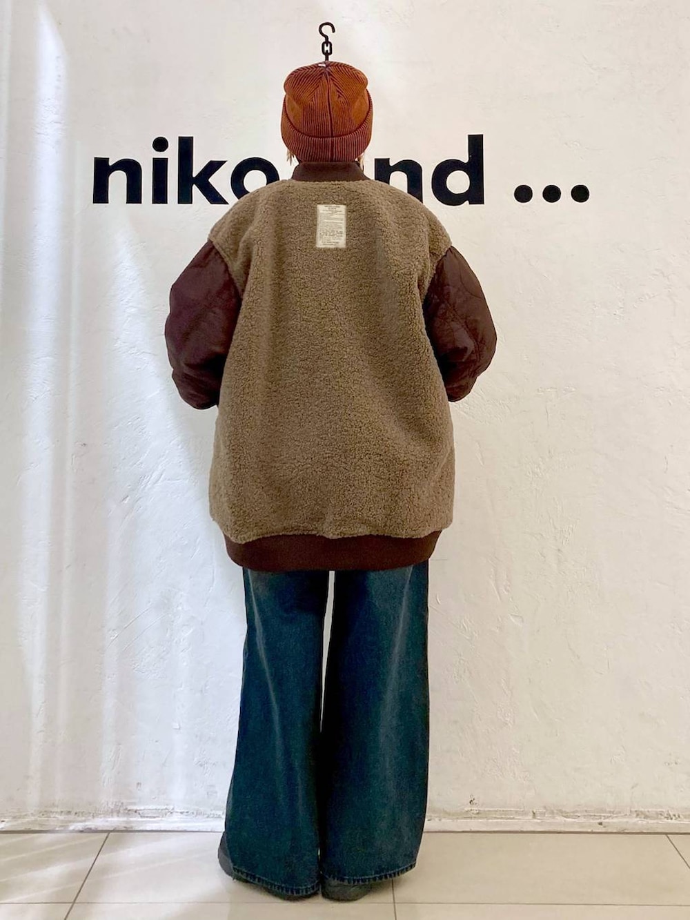 レッド系のMA-1、ベージュ系のニット/セーター、オレンジ系のニットキャップ/ビーニーを着用したレディースの秋コーディネートの5枚目の写真