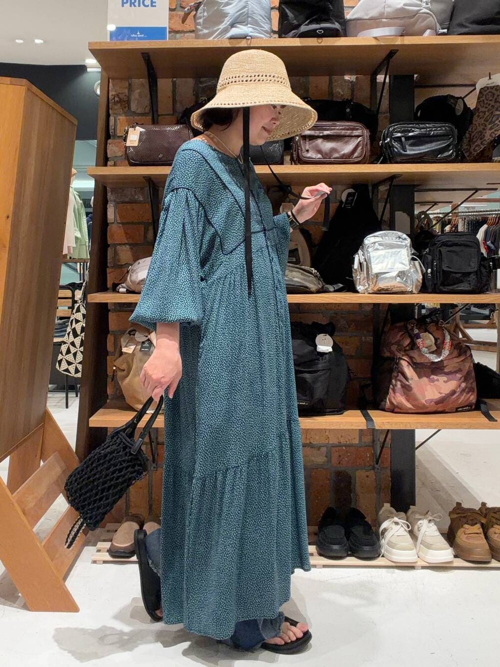 ブルー系のデニムパンツ、ブルー系のワンピース、ブラック系のトートバッグを着用したレディースの春コーディネートの6枚目の写真
