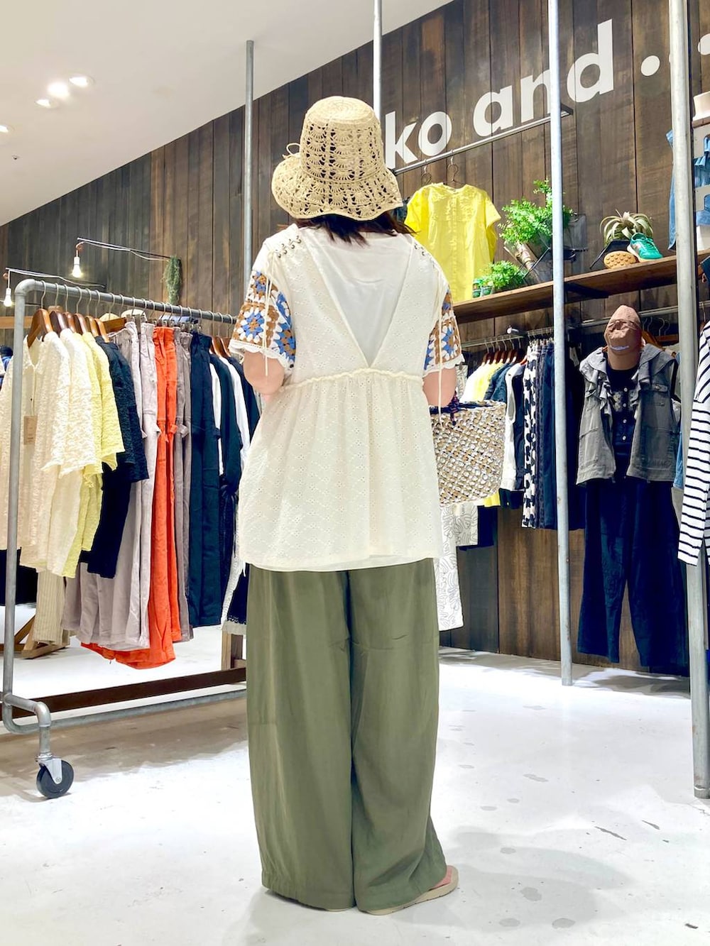 ホワイト系のベスト、ベージュ系のサンダル、グレー系のかごバッグを着用したレディースの夏コーディネートの4枚目の写真