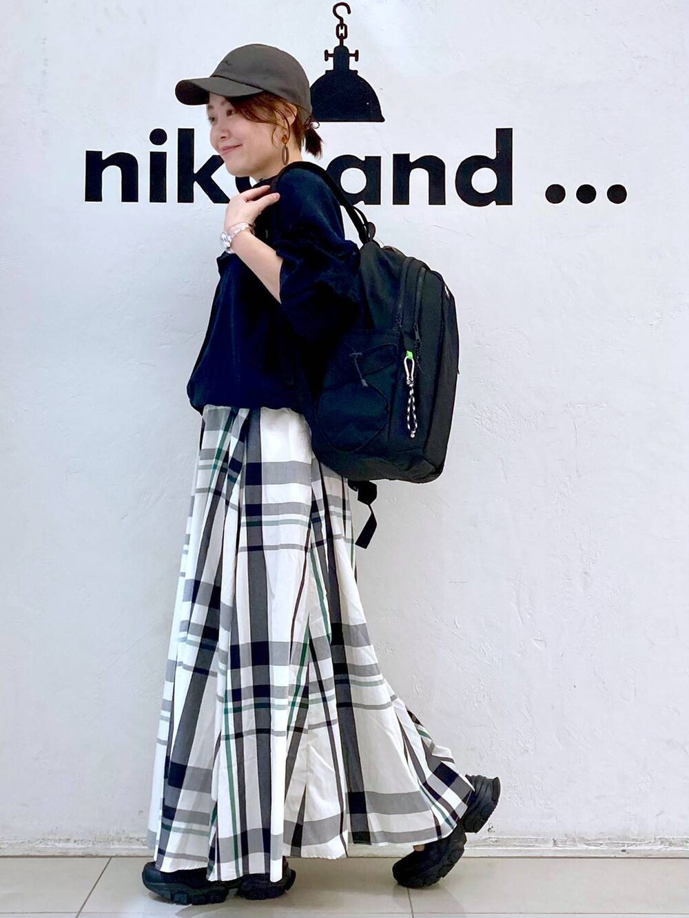 ブラック系のバックパック/リュック、ブラック系のシャツ/ブラウス、ベージュ系のスカートを着用したレディースの春コーディネートの4枚目の写真