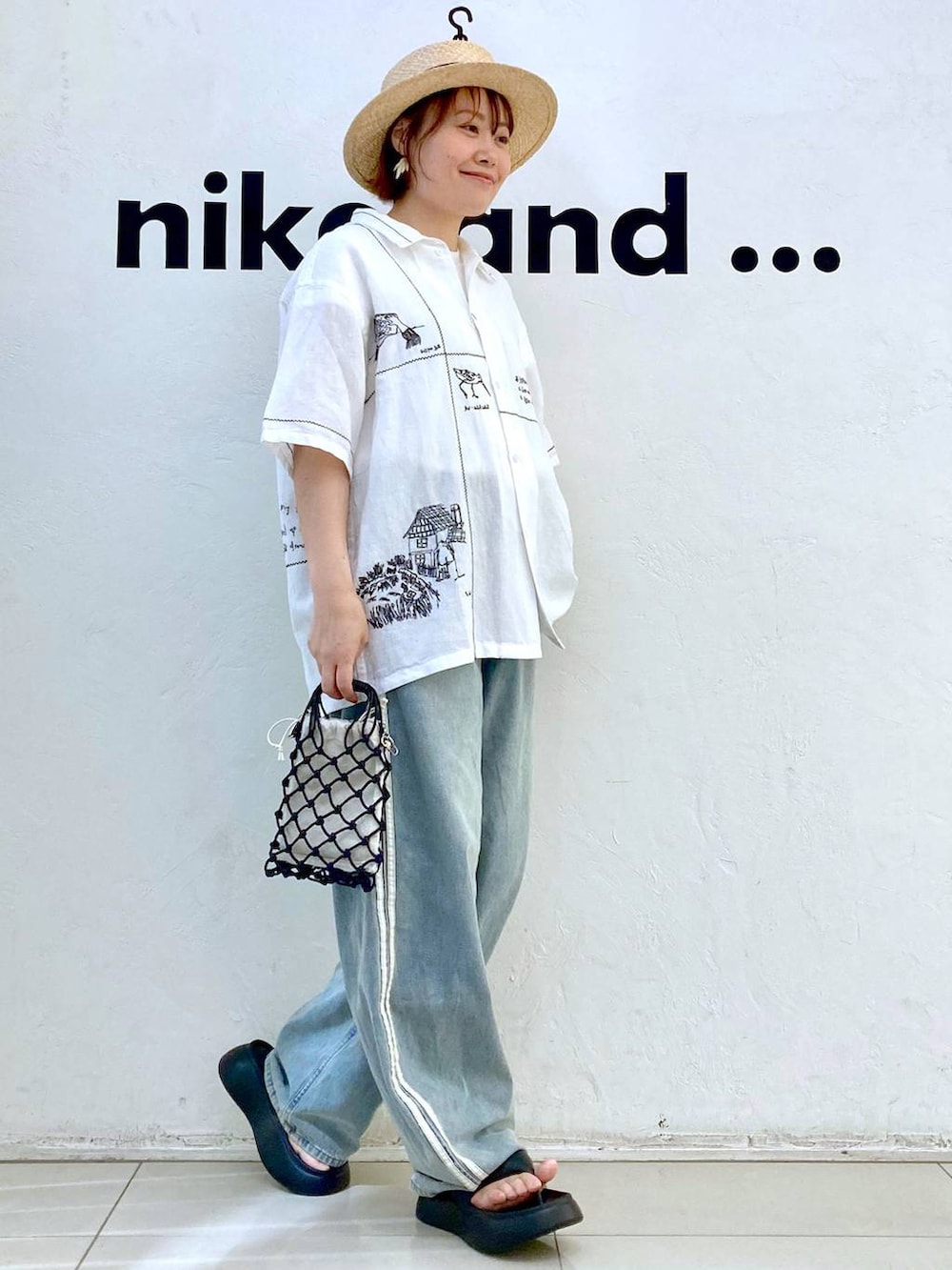 ブラック系のショルダーバッグ、ブラック系のサンダル、ホワイト系のTシャツ/カットソーを着用したレディースの春コーディネートの2枚目の写真