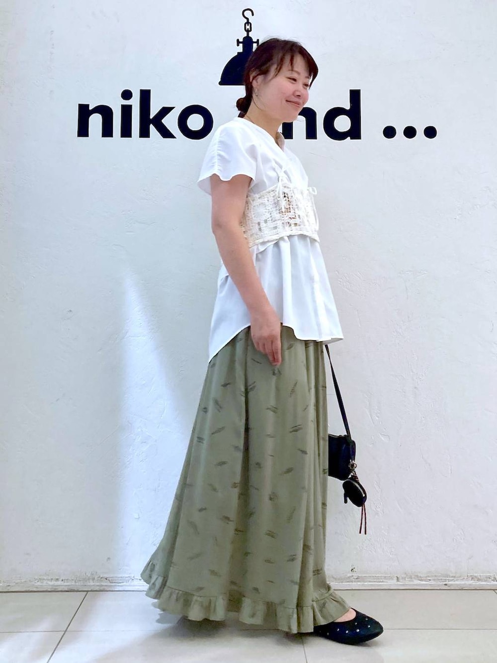 ブラック系のパンプス、ブラック系のショルダーバッグ、グリーン系のスカートを着用したレディースの夏コーディネートの5枚目の写真