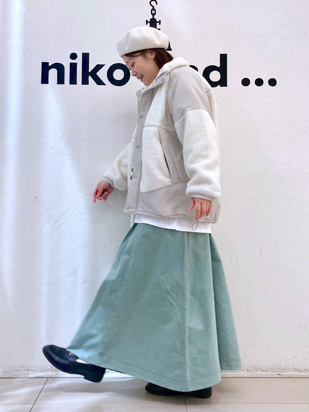 ベージュ系のベスト、ベージュ系のブルゾン、グリーン系のスカートを着用したレディースの冬コーディネートの3枚目の写真