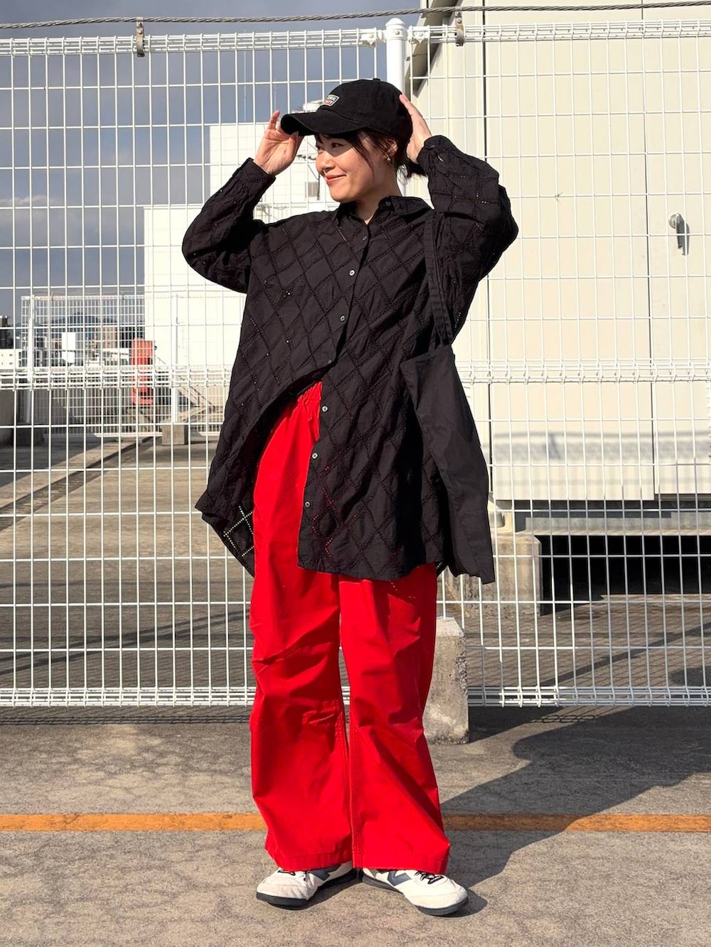 ブラック系のトートバッグ、ブラック系のチュニック、オレンジ系のその他パンツを着用したレディースの春コーディネートの3枚目の写真