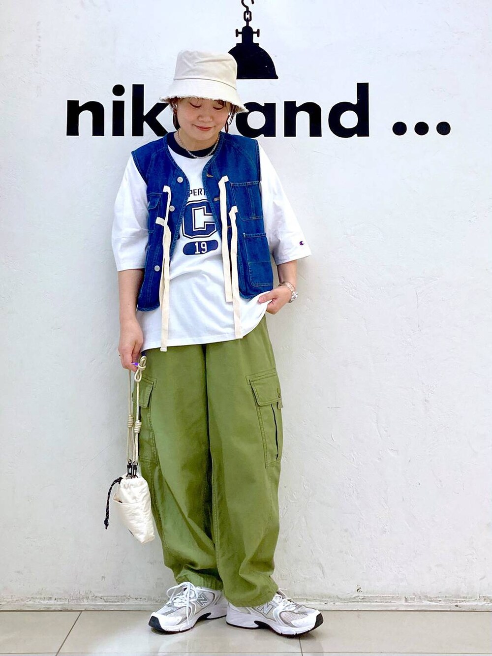 ブルー系のベスト、ベージュ系のショルダーバッグ、グリーン系のカーゴパンツを着用したレディースの春コーディネートの2枚目の写真