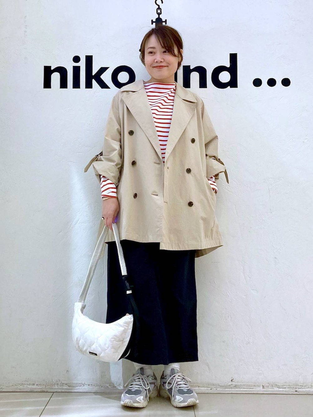 ベージュ系のトレンチコート、ベージュ系のショルダーバッグ、ブラック系のスカートを着用したレディースの春コーディネートの2枚目の写真