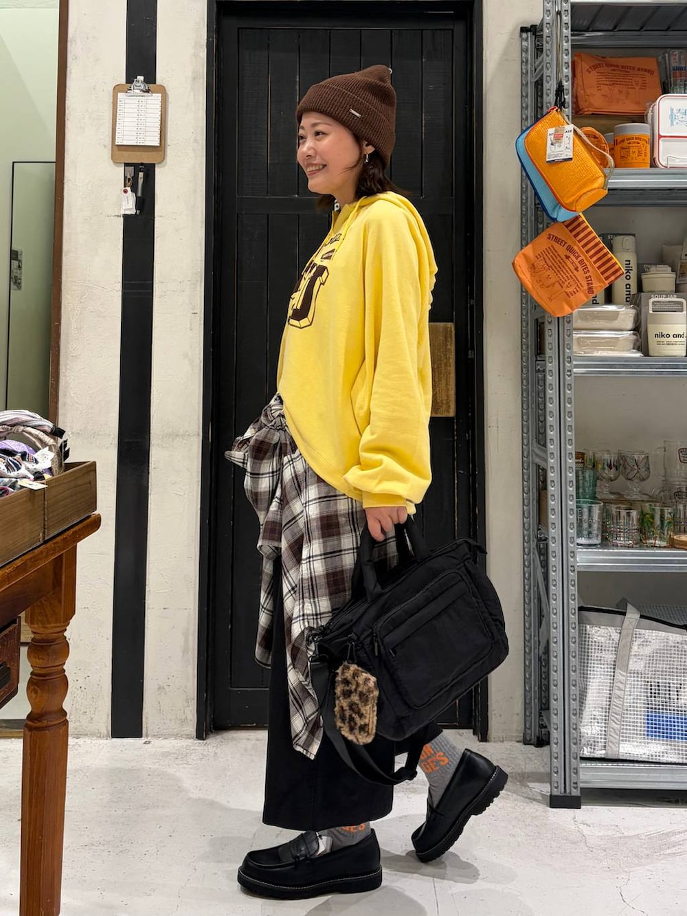 イエロー系のパーカー、ブラック系のその他パンツ、ブラック系のトートバッグを着用したレディースの秋コーディネートの3枚目の写真
