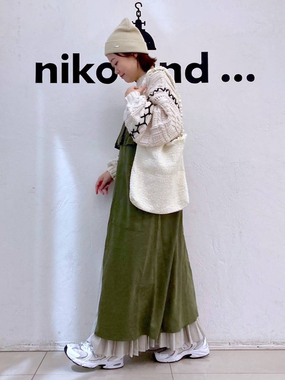 グリーン系のジャンパースカート、ベージュ系のショルダーバッグ、ベージュ系のニット/セーターを着用したレディースの冬コーディネートの3枚目の写真