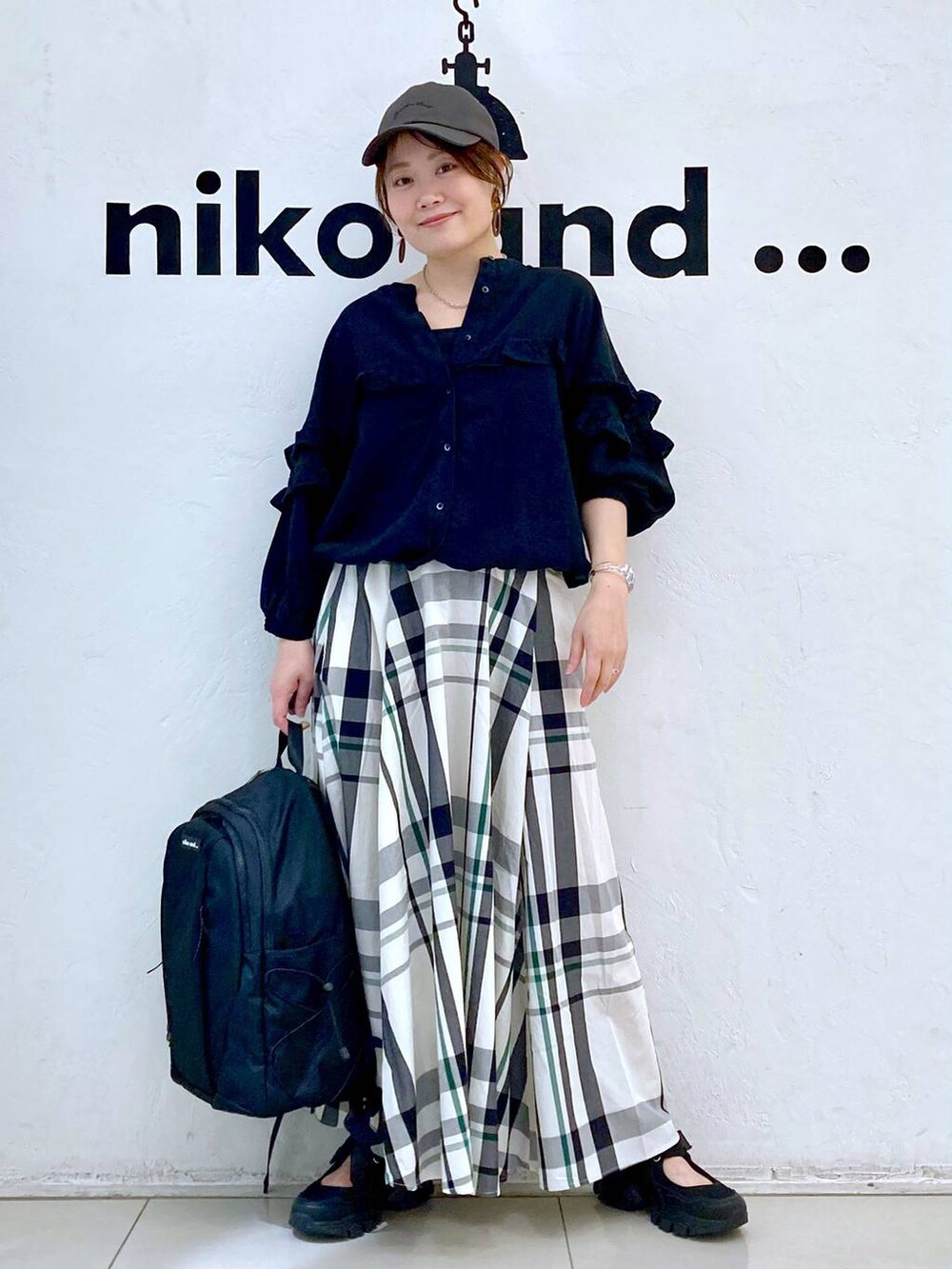 ブラック系のバックパック/リュック、ブラック系のシャツ/ブラウス、ベージュ系のスカートを着用したレディースの春コーディネートの3枚目の写真