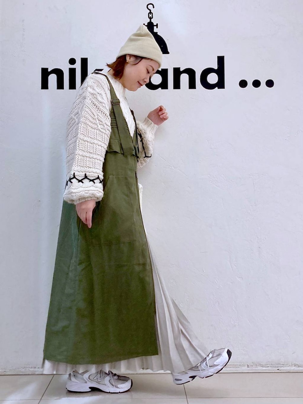 グリーン系のジャンパースカート、ベージュ系のショルダーバッグ、ベージュ系のニット/セーターを着用したレディースの冬コーディネートの5枚目の写真