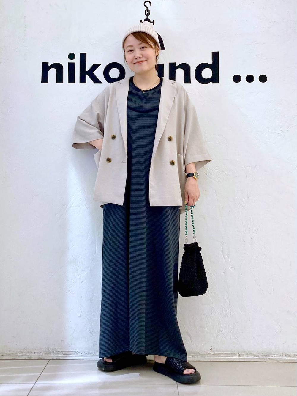 ブラック系のショルダーバッグ、ベージュ系のテーラードジャケット、ブラック系のサンダルを着用したレディースの夏コーディネートの5枚目の写真