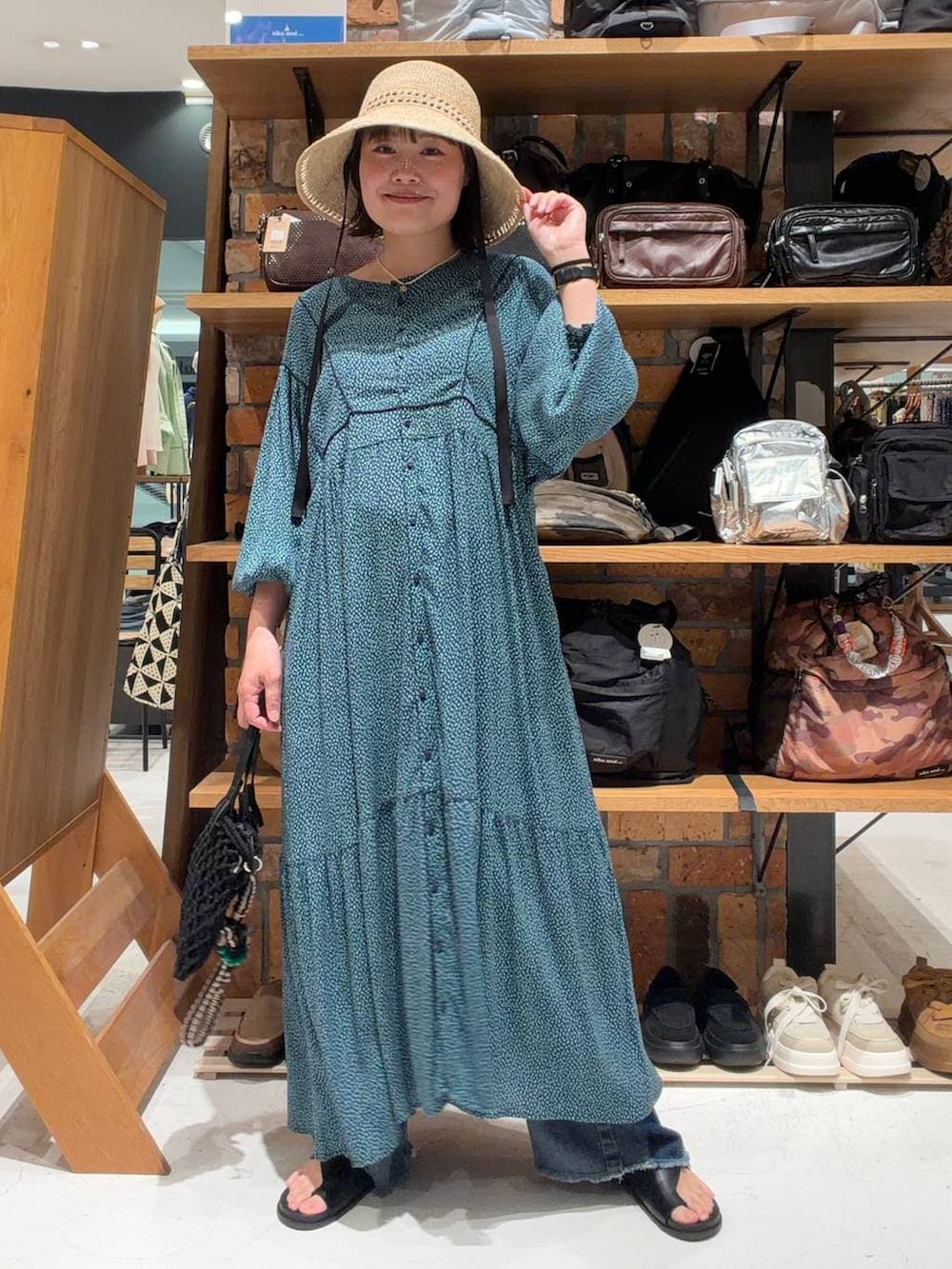 ブルー系のデニムパンツ、ブルー系のワンピース、ブラック系のトートバッグを着用したレディースの春コーディネートの2枚目の写真
