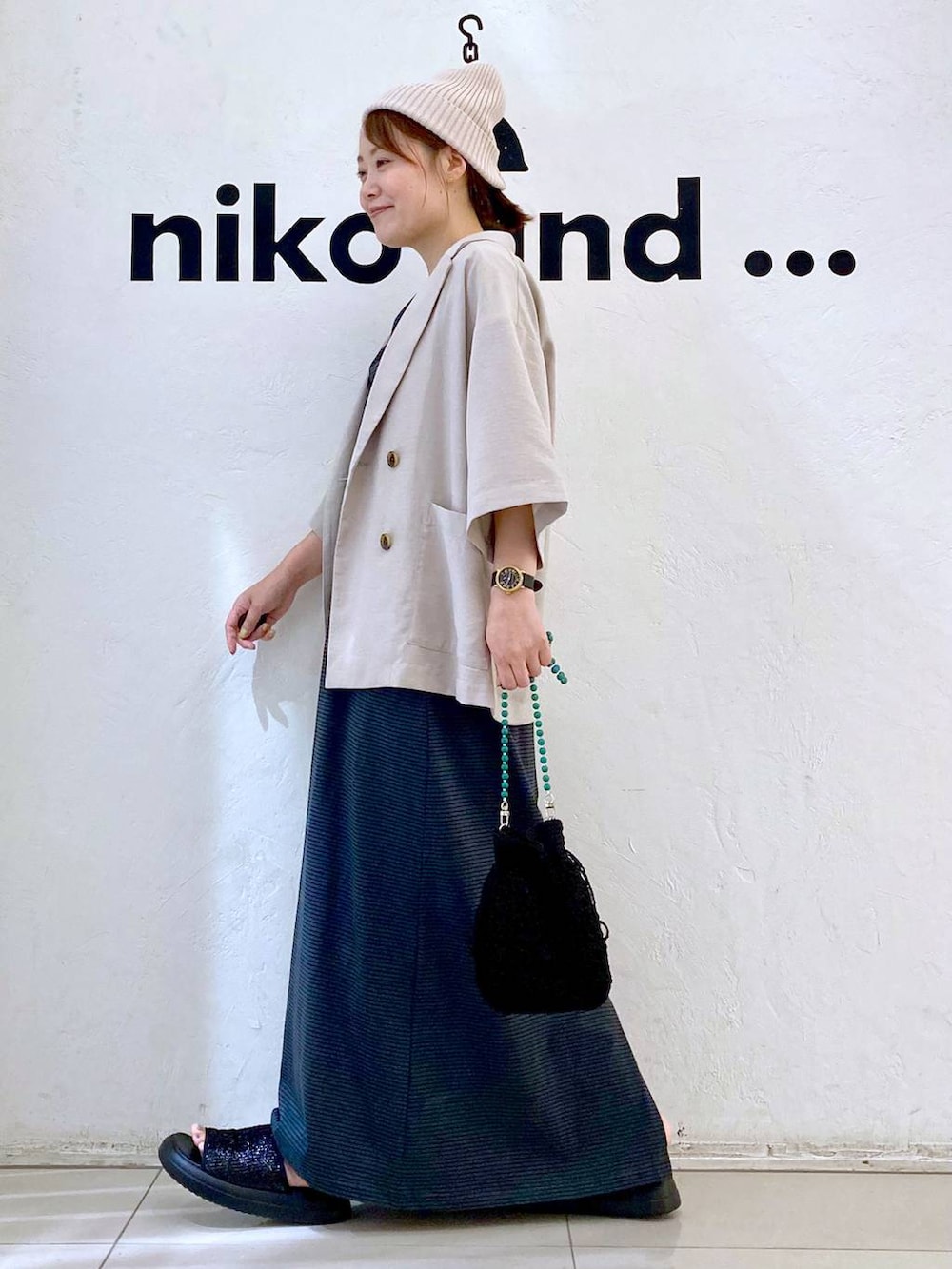 ブラック系のショルダーバッグ、ベージュ系のテーラードジャケット、ブラック系のサンダルを着用したレディースの夏コーディネートの2枚目の写真