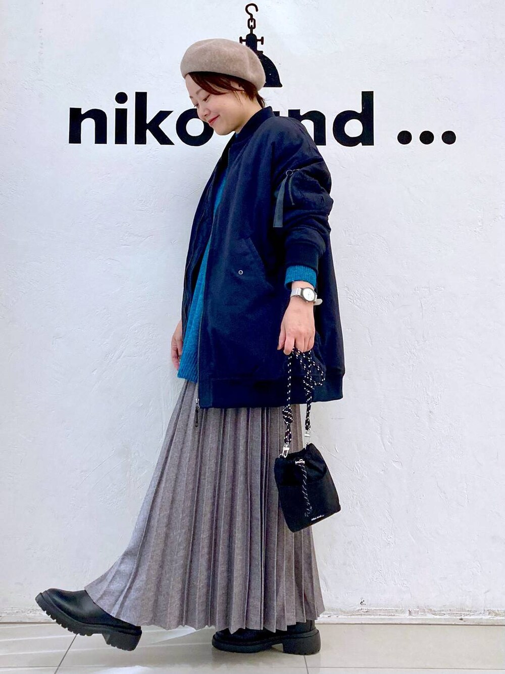 ブラック系のMA-1、グリーン系のニット/セーター、ブラック系のブーツを着用したレディースの冬コーディネートの2枚目の写真