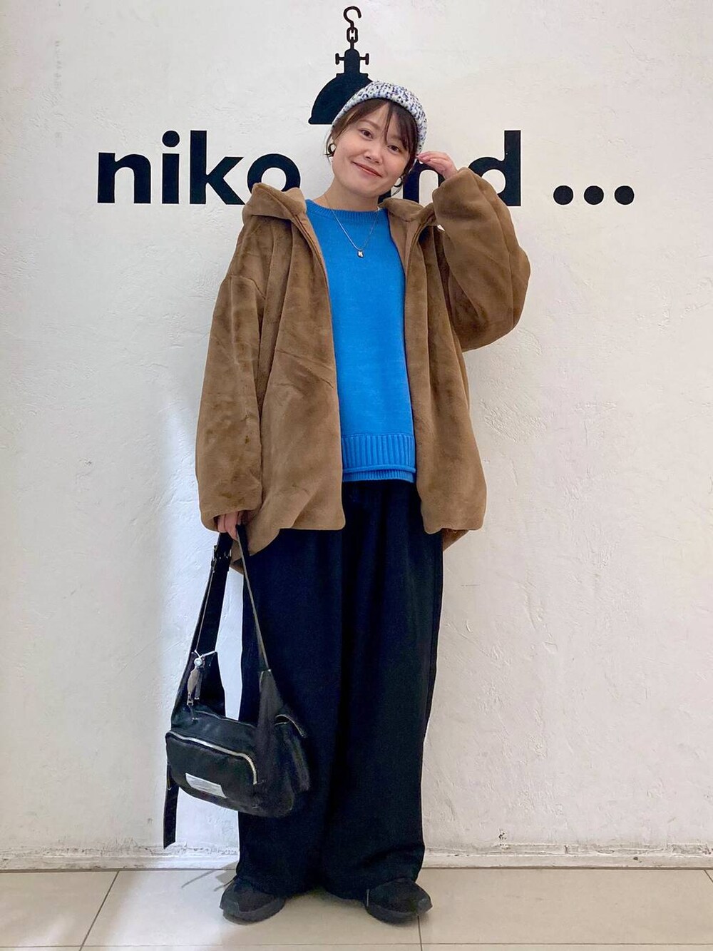 ホワイト系のTシャツ/カットソー、ブルー系のニット/セーター、ブラウン系のブルゾンを着用したレディースの秋コーディネートの2枚目の写真