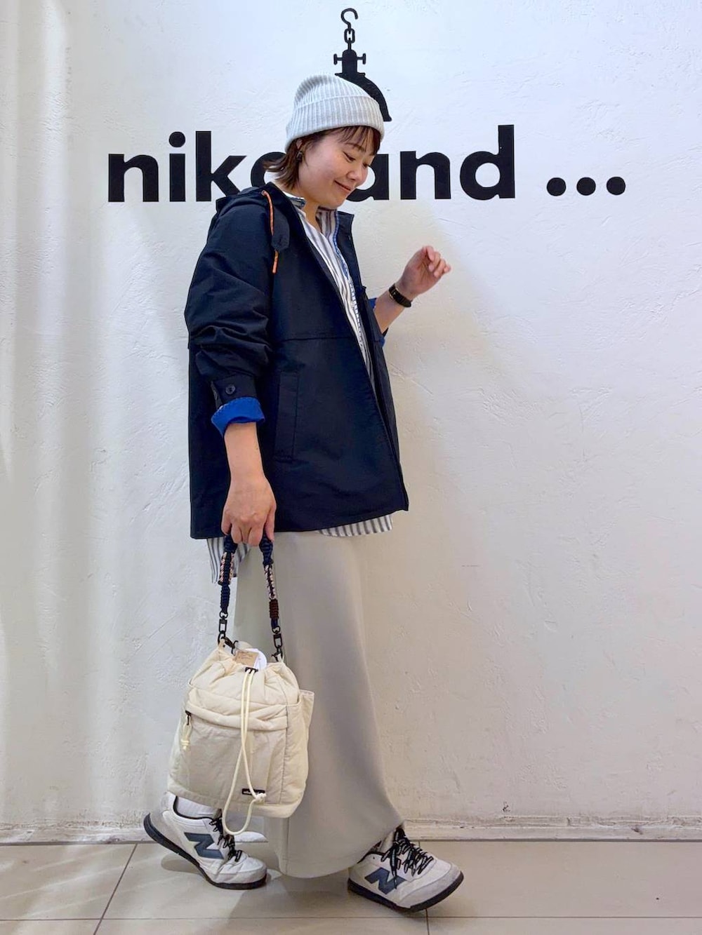 グレー系のタンクトップ、ベージュ系のスカート、ベージュ系のショルダーバッグを着用したレディースの春コーディネートの5枚目の写真