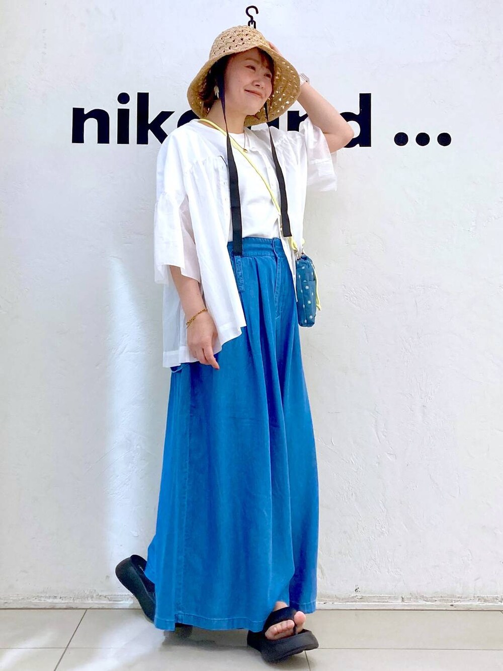 ブルー系のショルダーバッグ、ブラック系のサンダル、ブルー系のデニムパンツを着用したレディースの春コーディネートの5枚目の写真