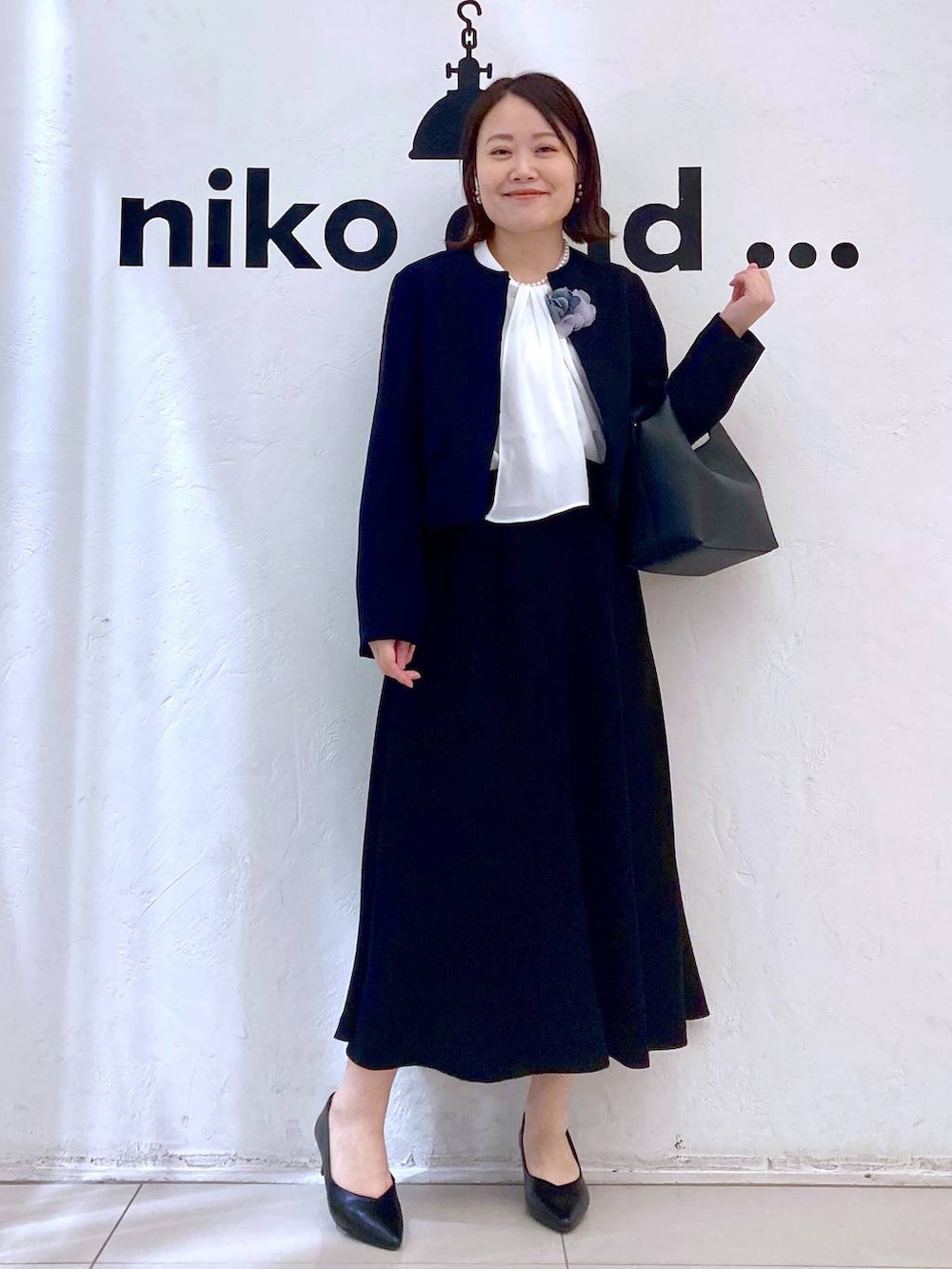 ホワイト系のシャツ/ブラウス、ブラック系のパンプス、ブラック系のノーカラージャケットを着用したレディースの冬コーディネートの2枚目の写真