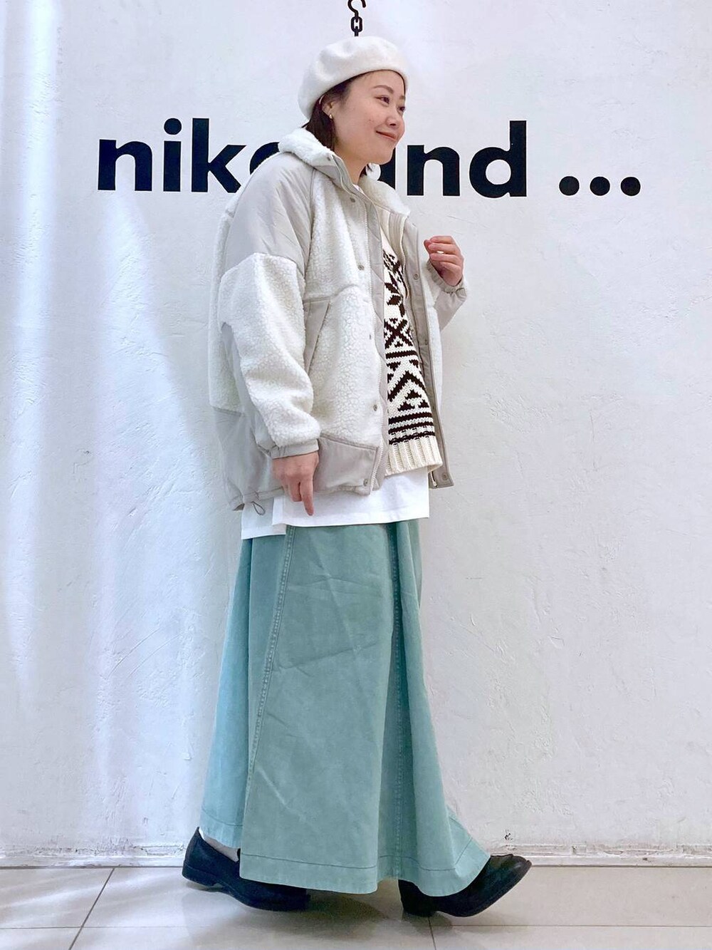 ベージュ系のベスト、ベージュ系のブルゾン、グリーン系のスカートを着用したレディースの冬コーディネートの4枚目の写真