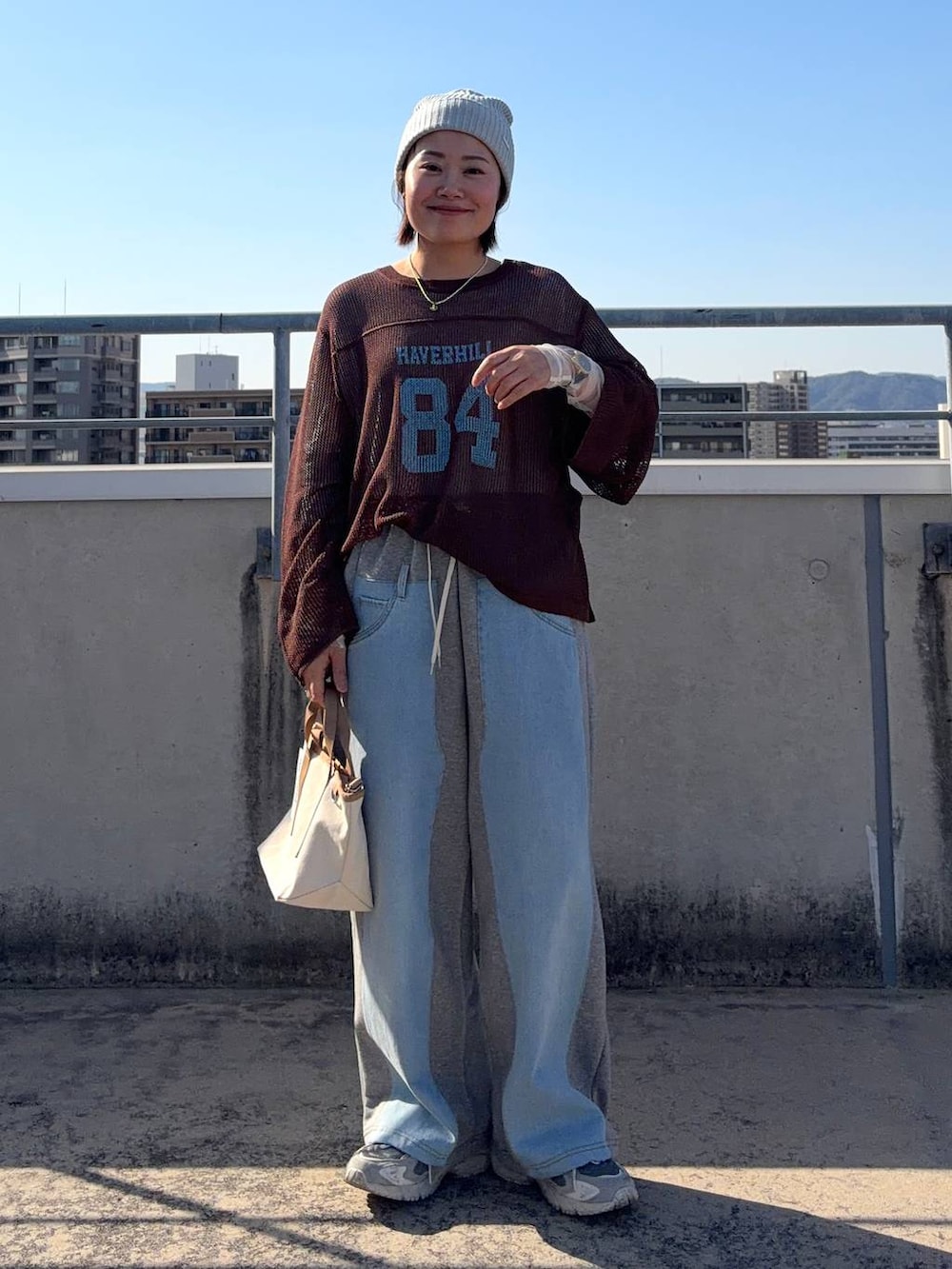 グレー系のデニムパンツ、ホワイト系のTシャツ/カットソー、その他のショルダーバッグを着用したレディースの春コーディネートの2枚目の写真