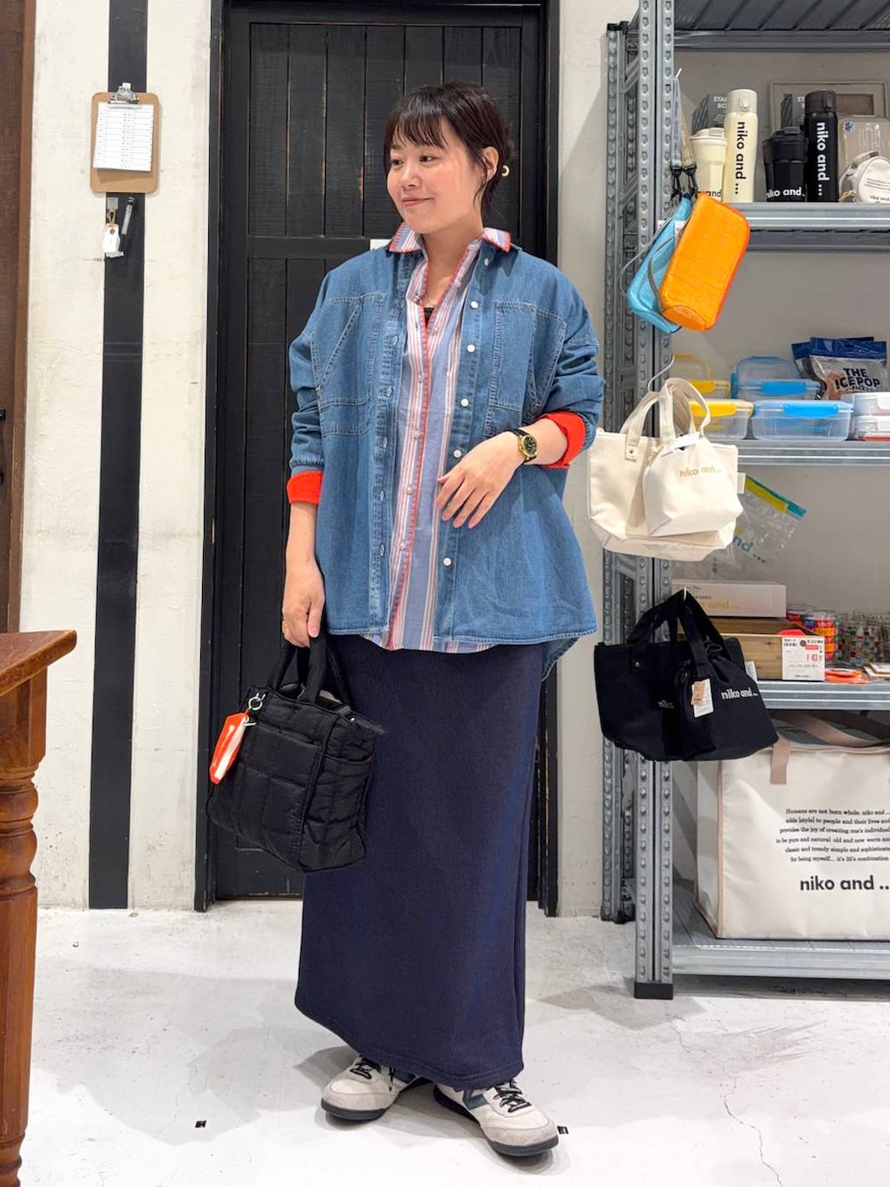 ブラック系のトートバッグ、ブルー系のスカート、その他のネックレスを着用したレディースの春コーディネートの2枚目の写真