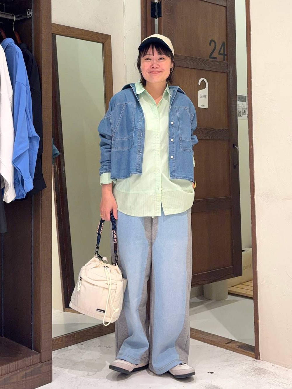 グレー系のデニムパンツ、グリーン系のシャツ/ブラウス、ベージュ系のショルダーバッグを着用したレディースの春コーディネートの2枚目の写真