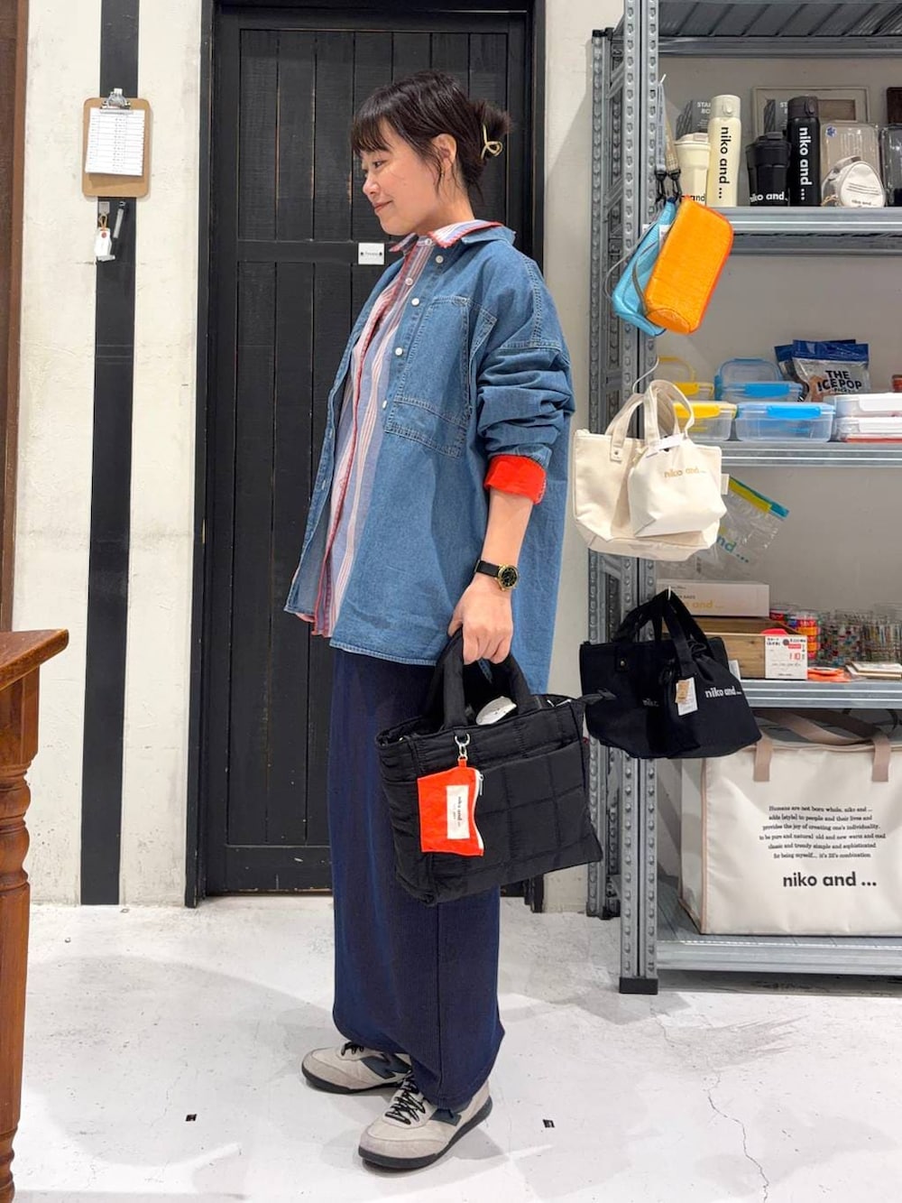 ブラック系のトートバッグ、ブルー系のスカート、その他のネックレスを着用したレディースの春コーディネートの3枚目の写真