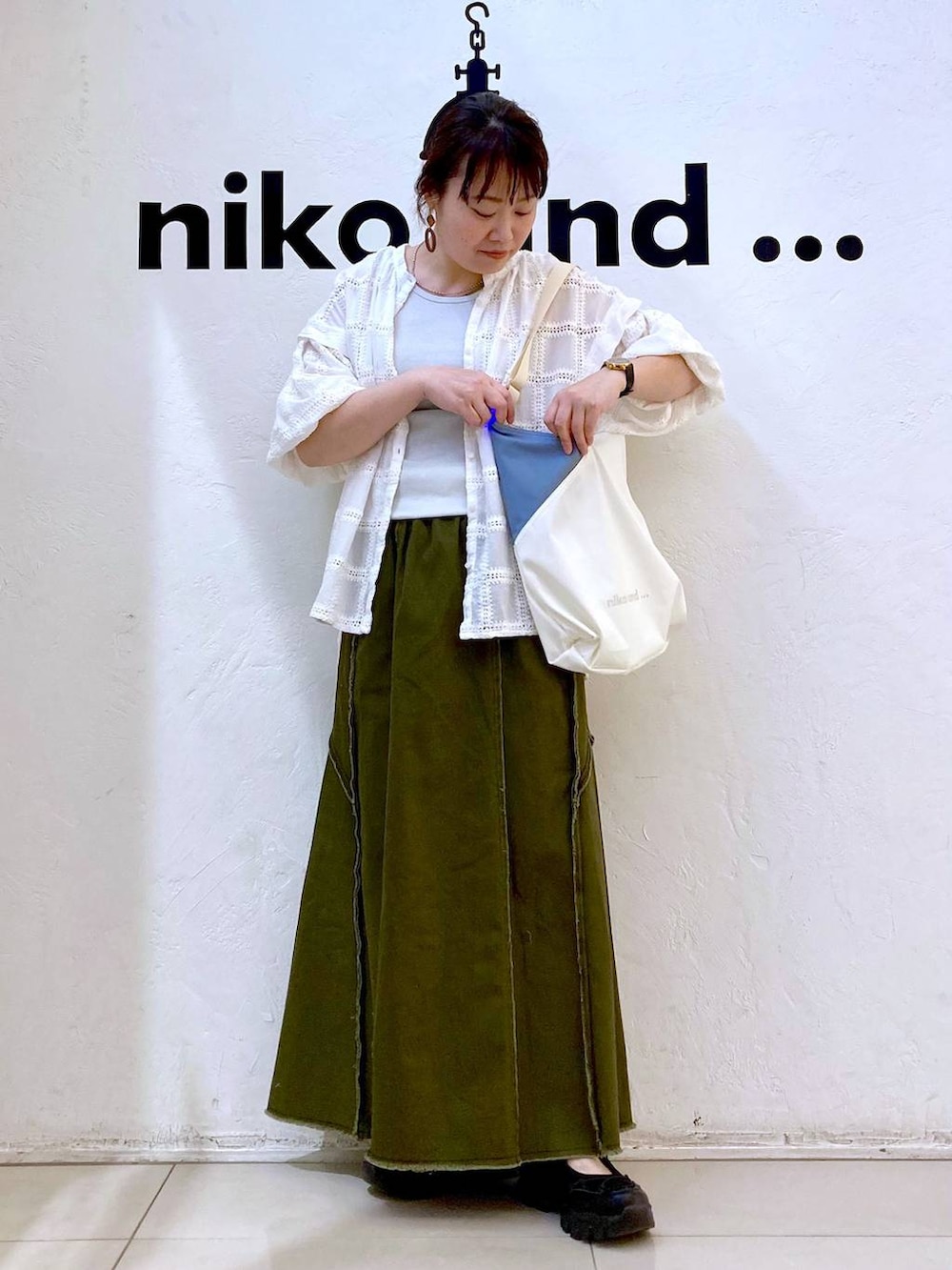 グレー系のタンクトップ、ベージュ系のトートバッグ、ブラック系のスニーカーを着用したレディースの春コーディネートの3枚目の写真