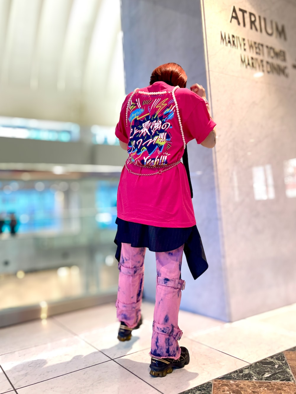 ピンク系のデニムパンツ、ブラック系のスニーカー、ピンク系のTシャツ/カットソーを着用したレディースの春コーディネートの2枚目の写真