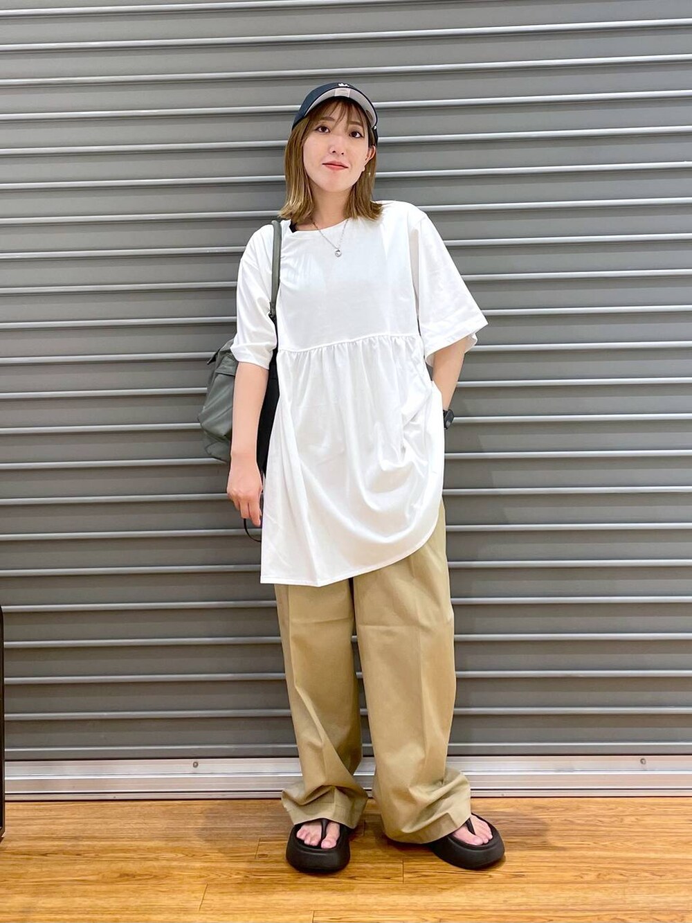 ブラック系のサンダル、グリーン系のショルダーバッグ、ホワイト系のTシャツ/カットソーを着用したレディースの夏コーディネートの2枚目の写真