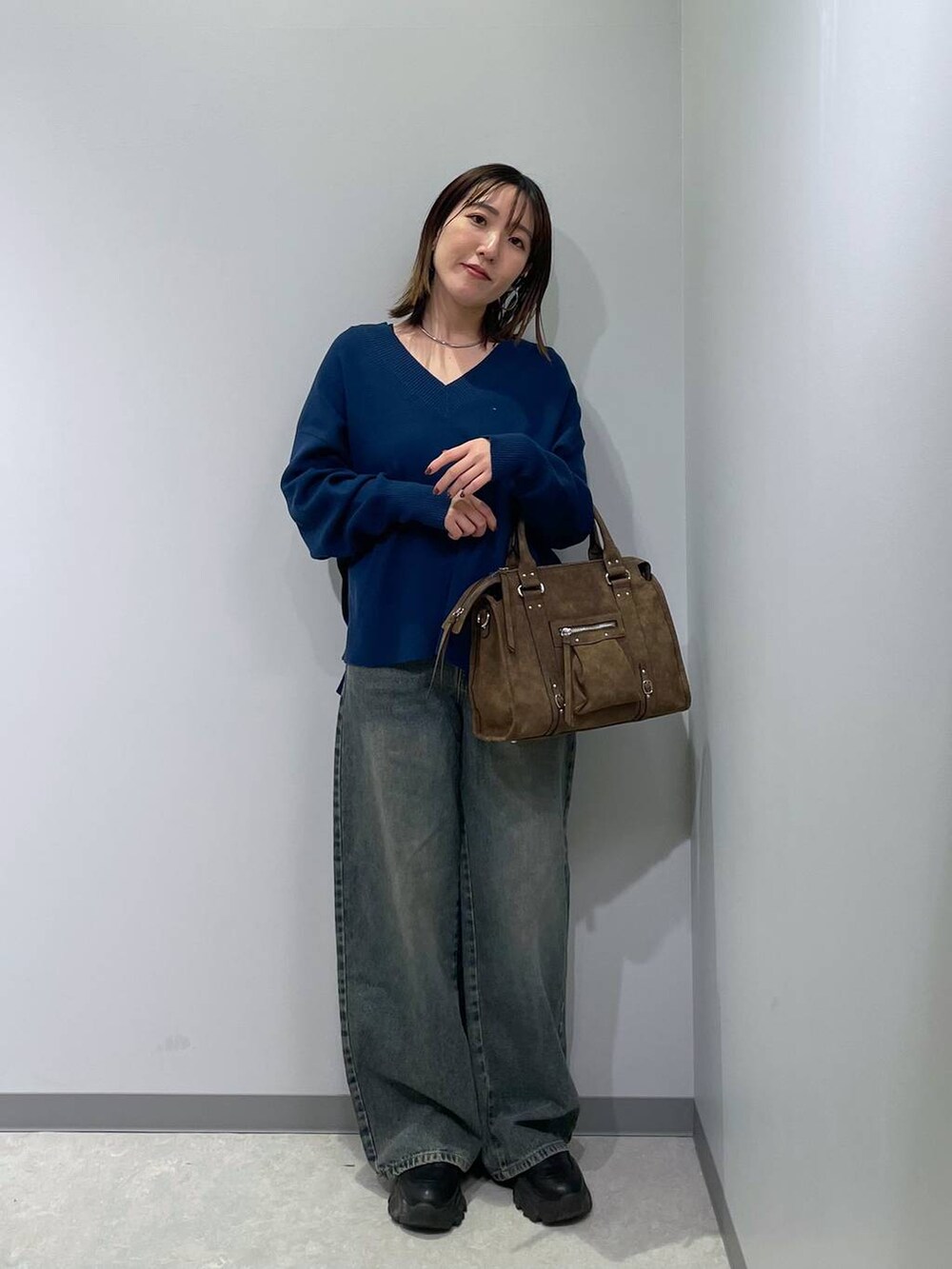 ブラウン系のボストンバッグ、ブルー系のニット/セーター、ブルー系のデニムパンツを着用したレディースの冬コーディネートの2枚目の写真