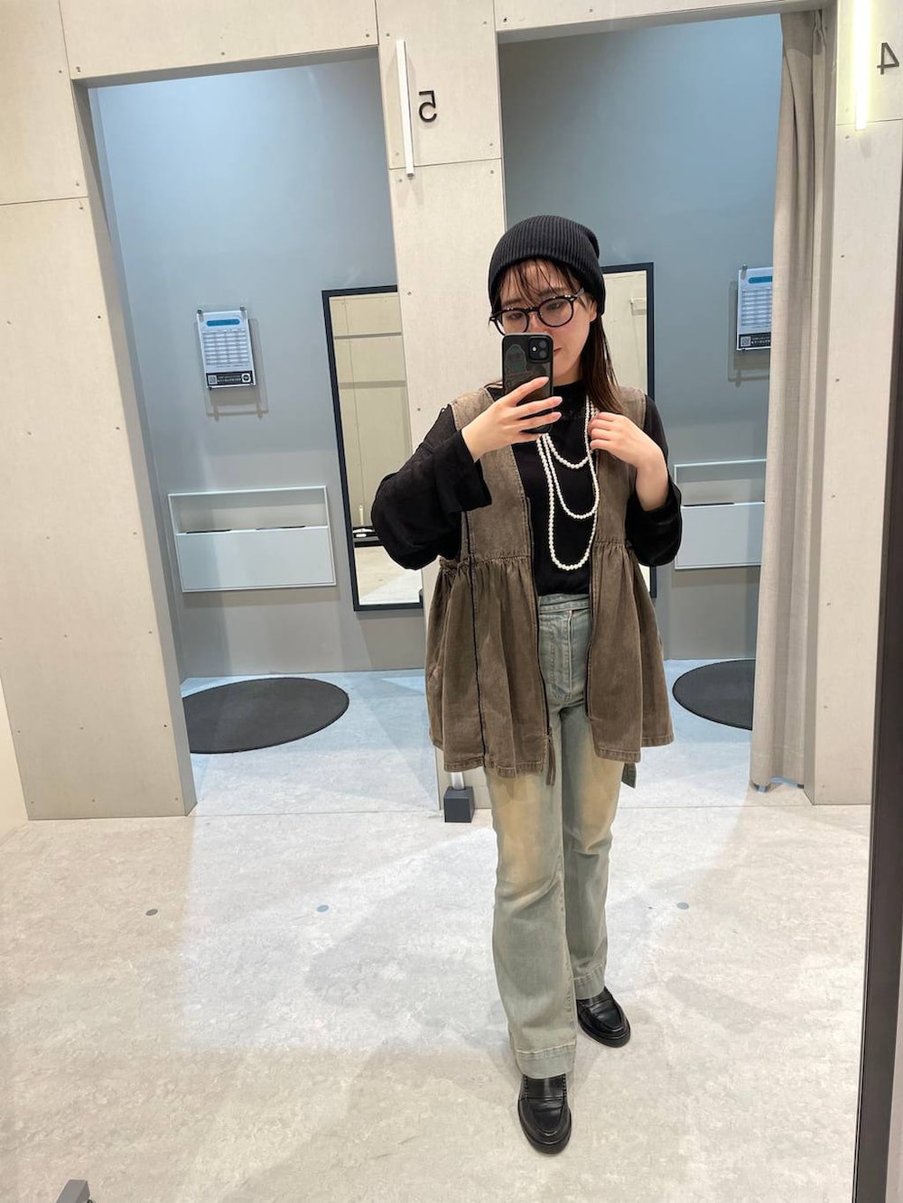 ブラウン系のベスト、ブルー系のデニムパンツを着用したレディースの春コーディネートの2枚目の写真