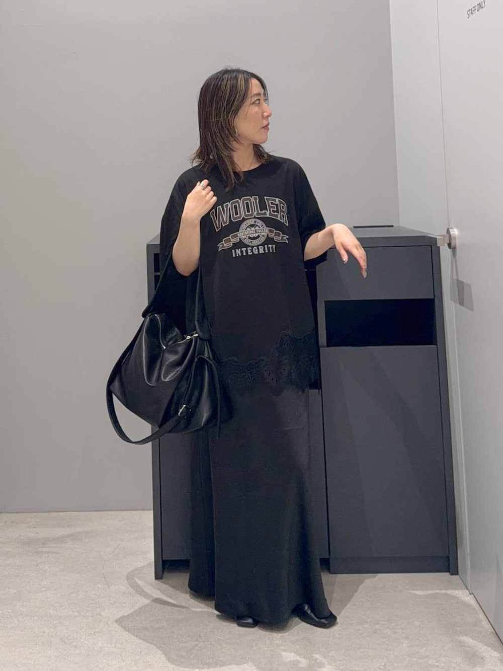 ブラック系のスカート、ブラック系のショルダーバッグ、グレー系のTシャツ/カットソーを着用したレディースの夏コーディネートの2枚目の写真