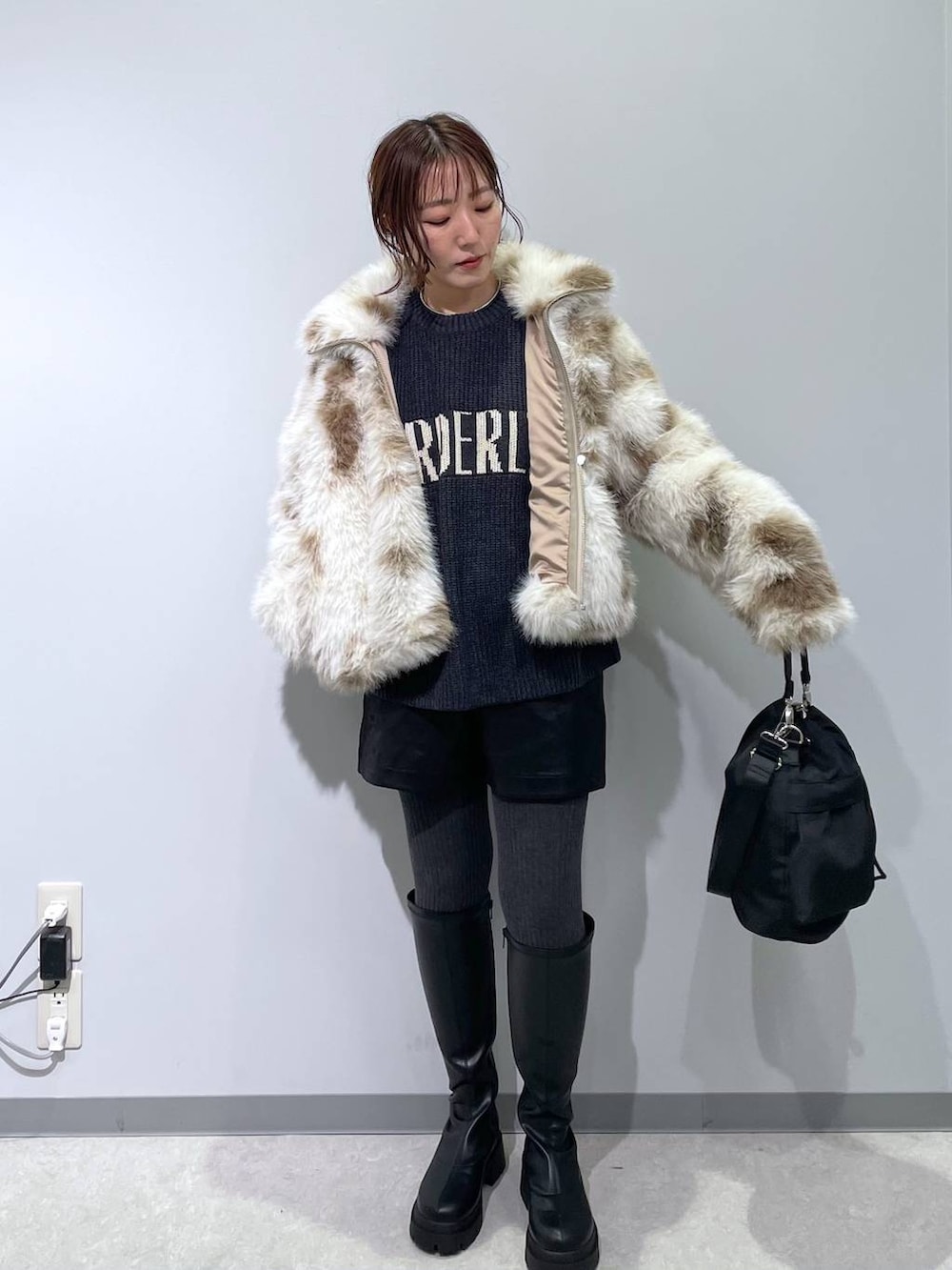 ホワイト系のブルゾン、ブラック系のショルダーバッグ、ブラック系のブーツを着用したレディースの冬コーディネートの4枚目の写真