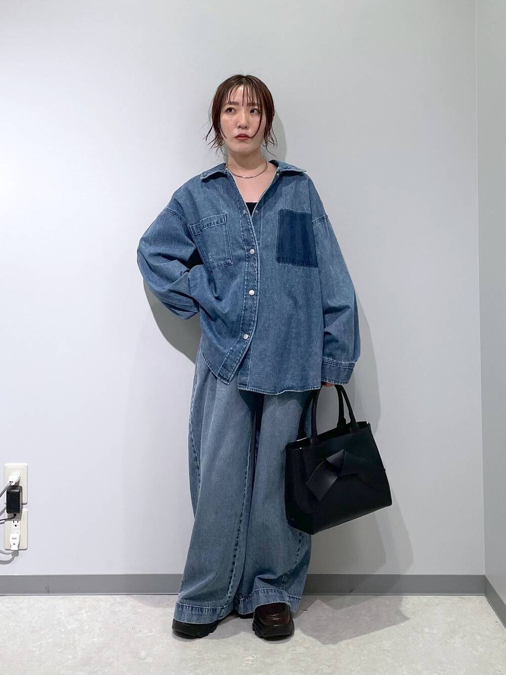 ブルー系のデニムパンツ、ブラック系のハンドバッグ、ブラウン系のローファーを着用したレディースの冬コーディネートの7枚目の写真