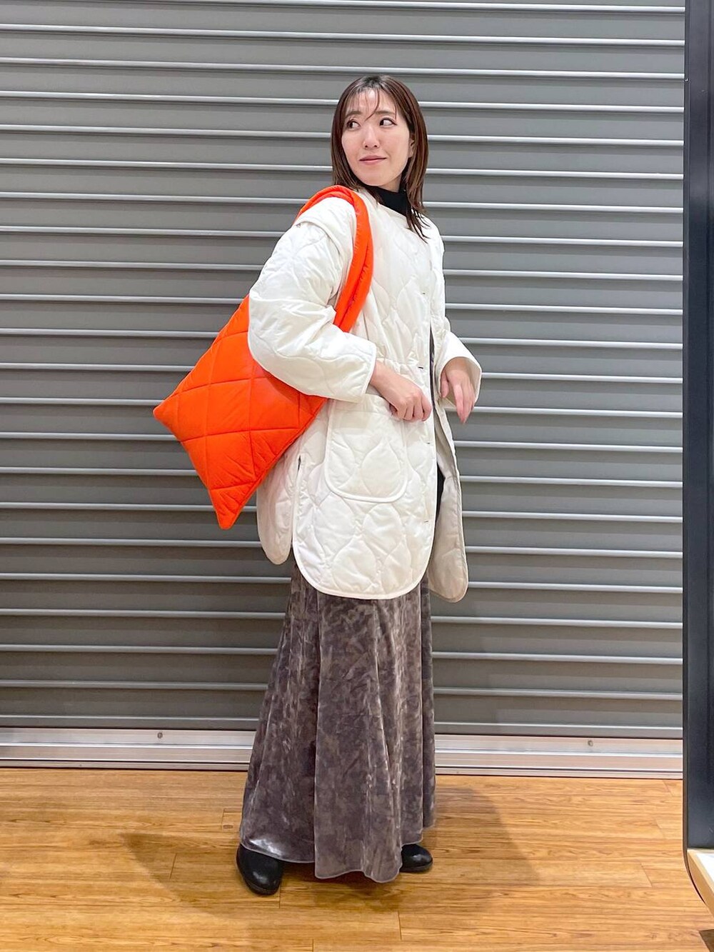 シルバー系のスカート、ホワイト系のその他アウター、ブラック系のチュニックを着用したレディースの冬コーディネートの2枚目の写真