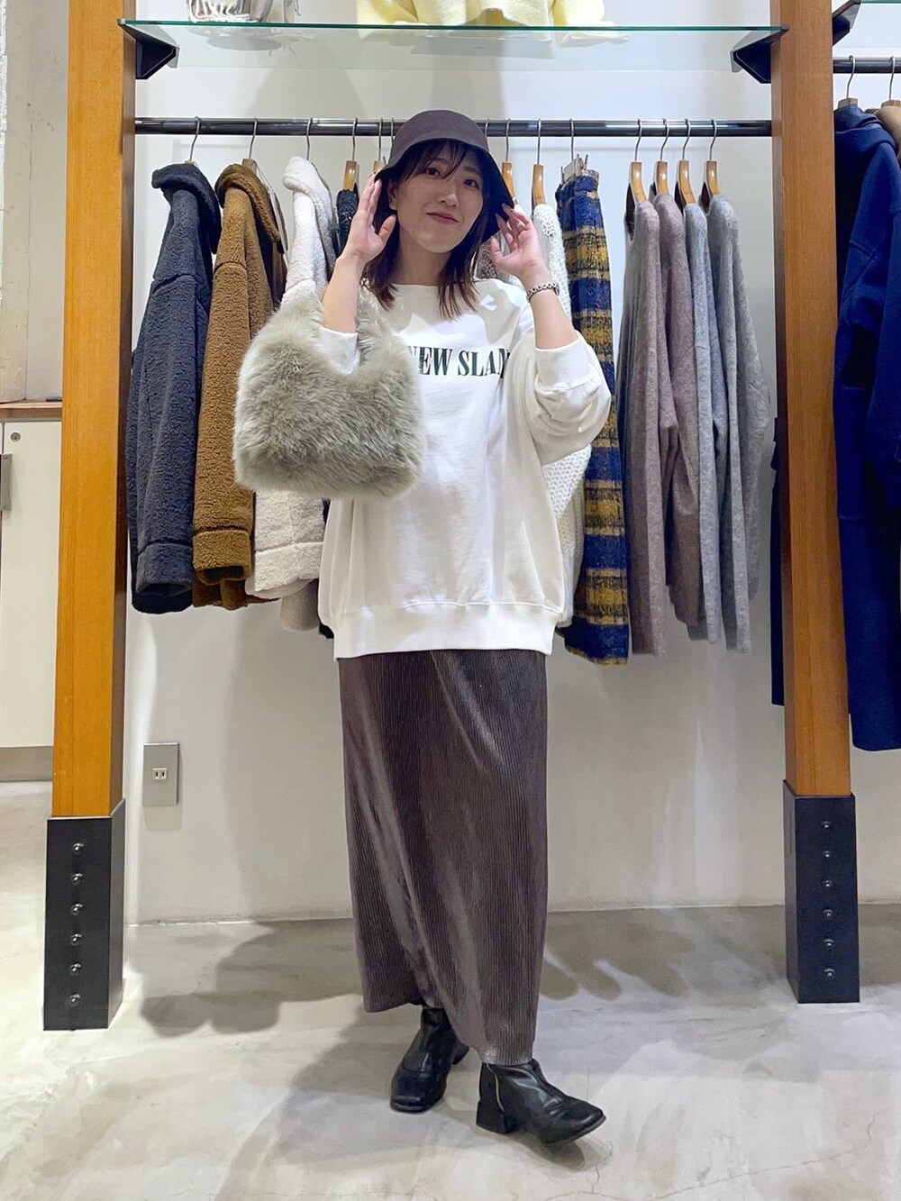 グレー系のハンドバッグ、ホワイト系のスウェット、シルバー系のスカートを着用したレディースの秋コーディネートの2枚目の写真