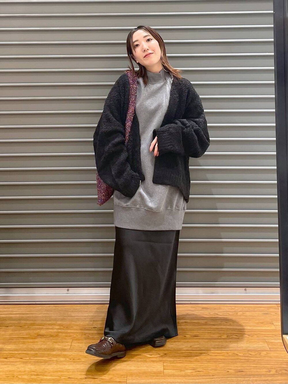 グレー系のチュニック、その他のショルダーバッグ、ブラック系のスカートを着用したレディースの冬コーディネートの2枚目の写真