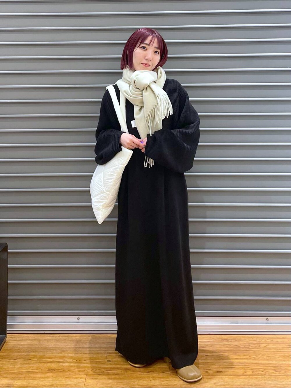 ブラック系のワンピース、ブラウン系のブーツ、ホワイト系のトートバッグを着用したレディースの冬コーディネートの2枚目の写真