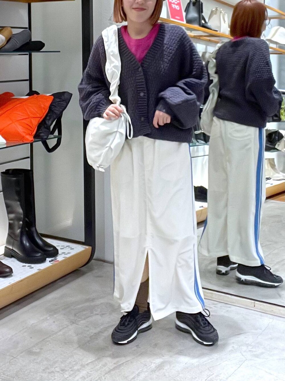 ホワイト系のスカート、レッド系のTシャツ/カットソー、グレー系のカーディガン/ボレロを着用したレディースの冬コーディネートの2枚目の写真