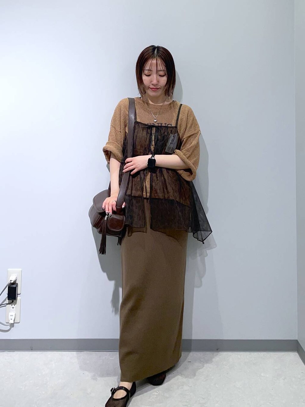 ブラウン系のスカート、ブラウン系のニット/セーター、ブラウン系のショルダーバッグを着用したレディースの夏コーディネートの2枚目の写真