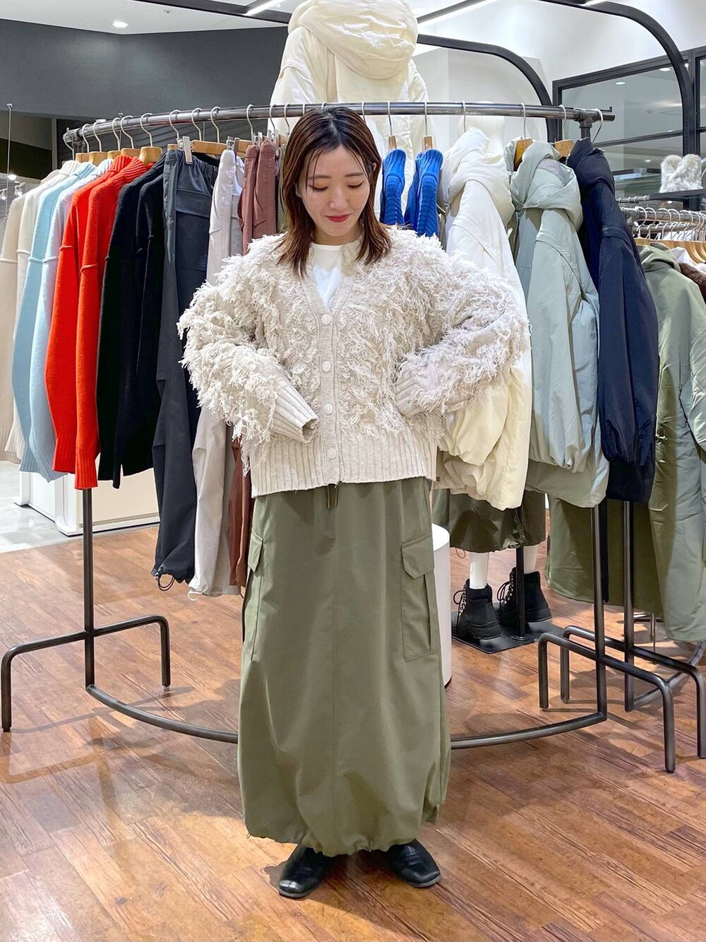 ホワイト系のTシャツ/カットソー、グリーン系のスカート、ホワイト系のカーディガン/ボレロを着用したレディースの冬コーディネートの3枚目の写真