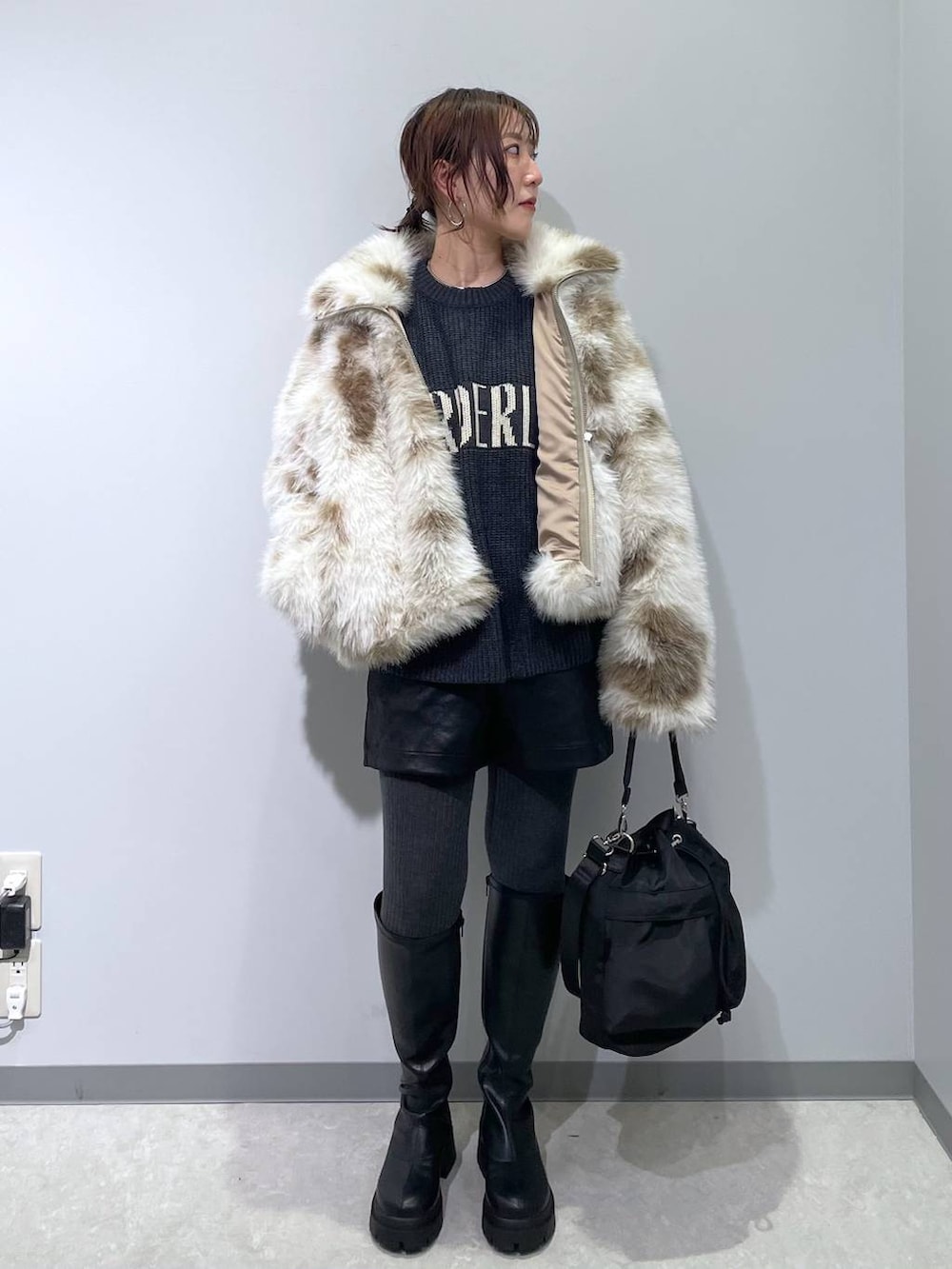 ホワイト系のブルゾン、ブラック系のショルダーバッグ、ブラック系のブーツを着用したレディースの冬コーディネートの3枚目の写真